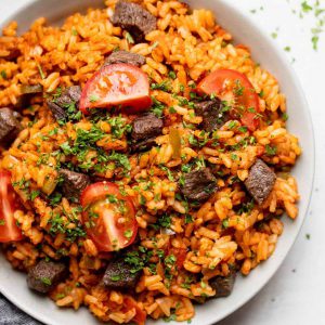 jollof rice served with vegetables, chopped fried beef